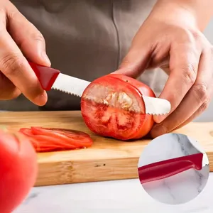 Close-up detail view showing the sharp serrated stainless steel blade cutting a tomato.