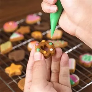 Vue détaillée montrant le processus de décoration de biscuits avec moules et poche à douille.