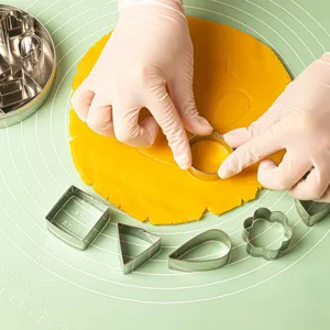 Gros plan détaillé du set d'emporte-pièces en acier inox avec pâte sur tapis de cuisson.