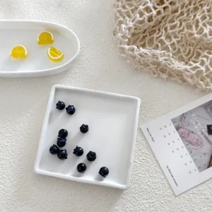 Detailed shot of handmade glass fruit beads, miniature blueberries and lemon slices for DIY crafts.