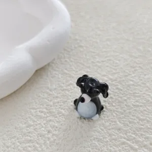 Close-up detail of a cute black and white glass animal charm, perfect for DIY handmade jewelry.
