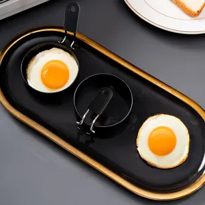 Non-stick fried egg mold detail view showing metallic ring and folding handle with cooked egg.