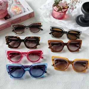 Primo piano dettagliato di occhiali da sole cat-eye multicolore su tessuto bianco.
