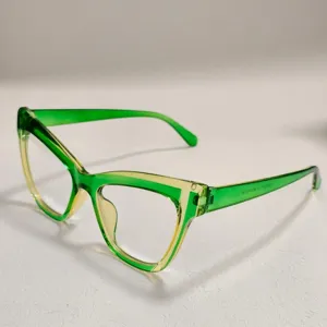 Toma de detalle de gafas de ojo de gato con degradado verde y amarillo y texto en la varilla.