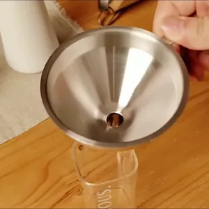 Stainless steel kitchen funnel detail showing practical liquid filtering and pouring over glass cup.