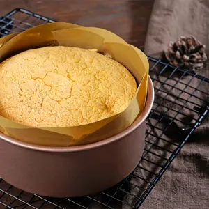 Moule a patisserie rond avec du papier cuisson et gateau sur grille pour la cuisine.