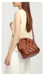 Stylish brown woven leather crossbody handbag featuring a unique triangle handle design for women.