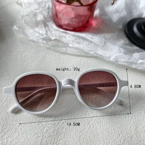 Vista detallada de gafas de sol vintage de moda con montura redonda y lentes degradadas blancas.