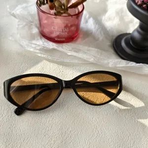 Vista detallada de gafas de sol estilo ojo de gato Y2K con montura negra y lentes marrones.