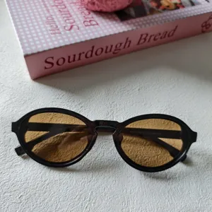 Vintage ovale Sonnenbrille mit braunen Gläsern und elegantem schwarzen Retro-Rahmen.