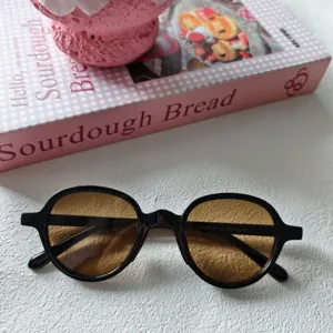 Primer plano detallado de gafas de sol retro con montura negra clásica y lentes marrones.