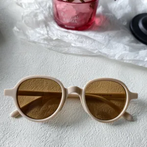 Primer plano de gafas de sol redondas retro, montura beige y lentes marrones, chic.