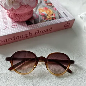 Primer plano de gafas de sol redondas vintage con lentes marrones degradadas y montura elegante.