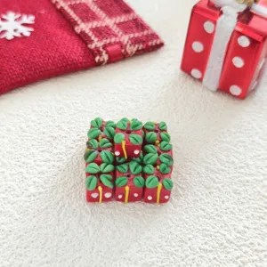 Close-up of cute red cube Christmas gift charms with green leaf accents for DIY crafts.