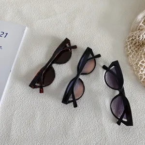 Primer plano de gafas de sol retro cat-eye con monturas pequeñas y lentes degradadas.