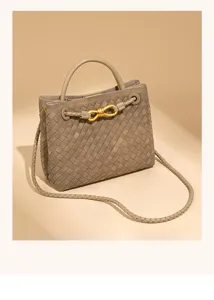 Woven leather handbag detail, elegant grey tote bag with gold metal knot and shoulder strap.