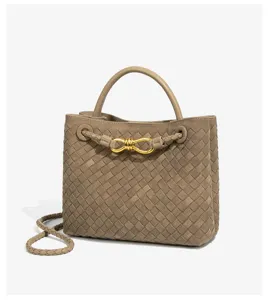 Close-up detail of luxury woven leather handbag featuring elegant metal knot closure and handle.