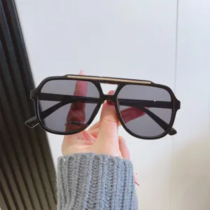 Lunettes de soleil aviateur noires tendance pour femmes et hommes avec barre dorée texturée.