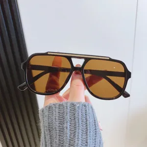 Lunettes de soleil tendance avec monture noire et verres marron pour une protection UV idéale.