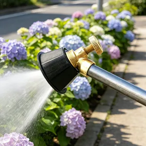 Detailed close-up view of the brass and black plastic garden spray nozzle spraying water mist.