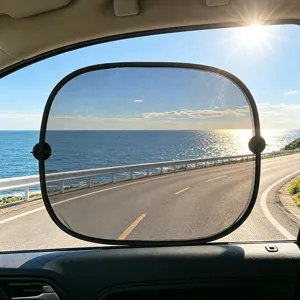 Parasole per finestrino laterale auto in rete nera installato con vista costiera panoramica.