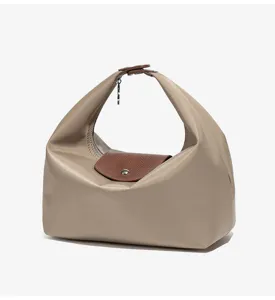 Minimalistische waterdichte nylon handtas met een bruine lederen flap en handvat.