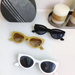 Detailed shot of trendy small round sunglasses in yellow, black, and white on surface.