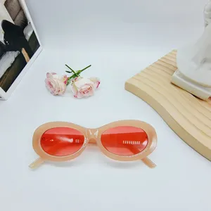 Detail view of trendy oval sunglasses featuring chic pink frames and vibrant red lenses.