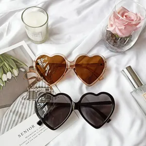 Vue détaillée de lunettes de soleil rétro en forme de cœur noir et marron sur un tissu blanc.