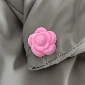 Gedetailleerde close-up van een roze camelia-bloemvormige dekbedclip met glad oppervlak.