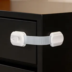 Detailfoto van wit kinderveiligheidsslot geïnstalleerd op meubels, verstelbare riem voor kasten.