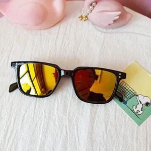 Close-up detail of trendy black square frame sunglasses featuring striking yellow reflective lenses.