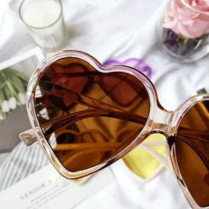 Gros plan détaillé de lunettes de soleil cœur rétro avec monture claire et verres dégradés.