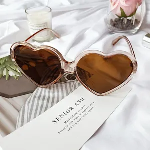 Vue détail de lunettes de soleil vintage en forme de cœur, verres bruns tendance et monture.