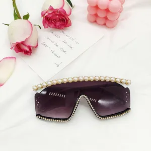 Gros plan sur les lunettes de soleil sans monture avec perles sur le bord et strass scintillants.