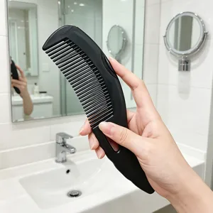 Detail view of a black plastic hair scalp massage comb, hollow design for easy daily hair care.