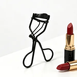 Scatto dettagliato di un piegaciglia nero con accessori di rossetto su fondo bianco pulito.