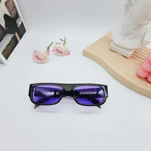 Detalle de gafas de sol vintage de moda con montura negra y lentes moradas estilo.