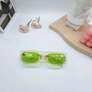 Vista detallada de gafas de sol retro con montura pequeña, lentes verdes y marco transparente.