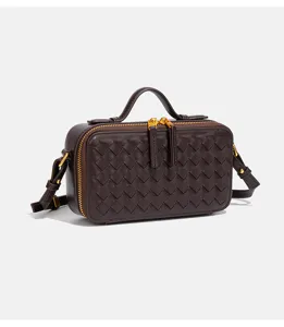Vue détaillée du mini sac bandoulière en cuir tressé marron foncé avec poignée et métal doré.