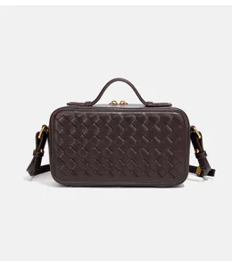 Gros plan de détail sur le sac fourre-tout en cuir tressé marron foncé, design structuré.