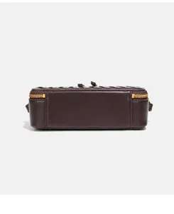 Détail latéral de mini sac boîte en cuir marron foncé, avec fermeture éclair dorée élégante.