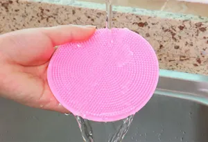 Close-up of pink silicone dish washing brush detail showing soft bristle texture rinsing in sink.