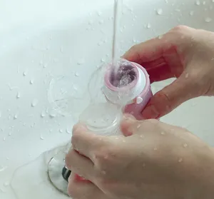 Silicone travel bottle detail view showing wide mouth design under running water rinsing.