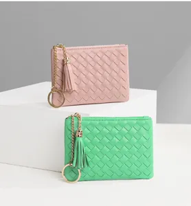Vue rapprochée de petits porte-monnaie en cuir tressé avec fermeture éclair et pompon.