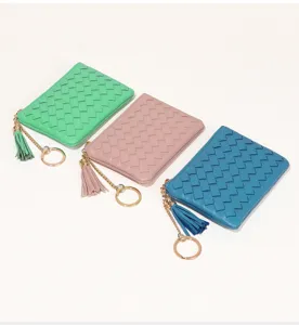 Détail des mini porte-monnaies tressés en cuir avec fermeture éclair et glands élégants.