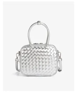 Détail de la texture en cuir métallisé tissé argenté du sac à main et de la bandoulière.