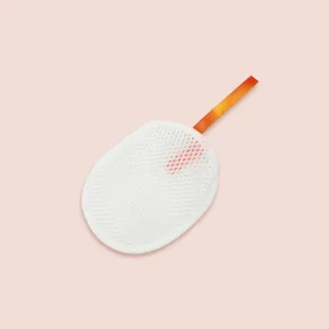 Detail shot of a white foaming net with an orange hanging ribbon for facial soap use.