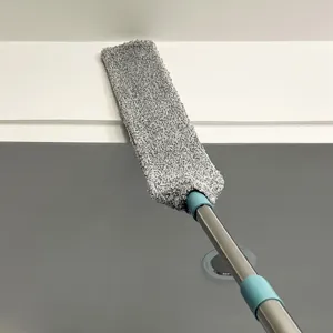 Vista detallada del plumero de microfibra gris limpiando esquinas altas con mango telescópico.