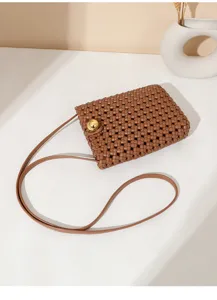 Brown woven mini crossbody phone bag detail view with gold tone round clasp on white background